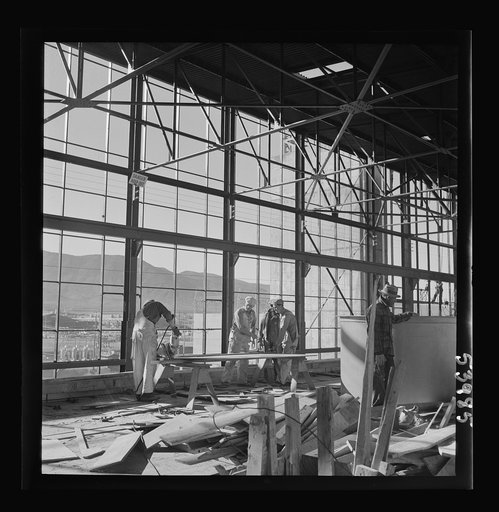 Untitled photo, possibly related to: Las Vegas, Nevada. Workmen busy with woodwork inside the steel structure of one of the buildings of the Basic Magnesium Incorporated plant. Much of the plant can be seen in the background, and beyond it loom high mountains