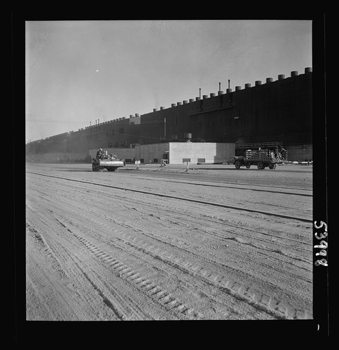 Untitled photo, possibly related to: Las Vegas, Nevada. Two series of buildings and a road between, filled with construction materials, on the grounds of the huge Basic Magnesium Incorporated plant in the southern Nevada desert