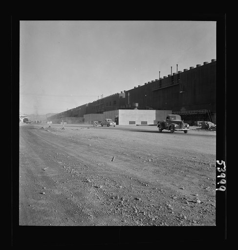 Untitled photo, possibly related to: Las Vegas, Nevada. Two series of buildings and a road between, filled with construction materials, on the grounds of the huge Basic Magnesium Incorporated plant in the southern Nevada desert