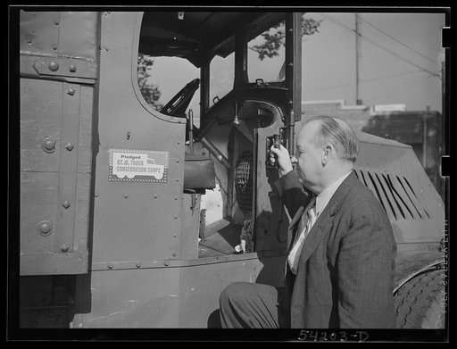 Untitled photo, possibly related to: Washington, D.C. A man looking at the motor of a commercial truck on the side of which is displayed a United States Truck Conservation Corps pledge