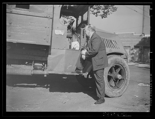 Untitled photo, possibly related to: Washington, D.C. A man looking at the motor of a commercial truck on the side of which is displayed a United States Truck Conservation Corps pledge