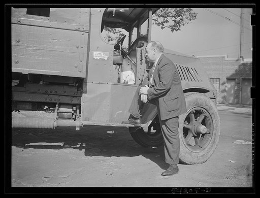 Untitled photo, possibly related to: Washington, D.C. A man looking at the motor of a commercial truck on the side of which is displayed a United States Truck Conservation Corps pledge