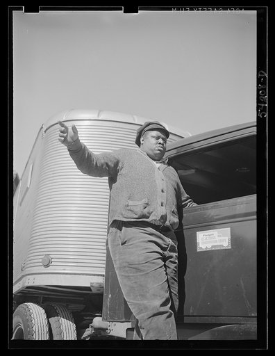 Untitled photo, possibly related to: Washington, D.C. A colored driver on the running board of an autocar van giving some directions to someone ahead. A pledge to the United States Truck Conservation Corps is displayed on the door of the car