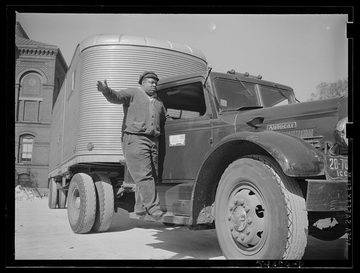 Untitled photo, possibly related to: Washington, D.C. A colored driver on the running board of an autocar van giving some directions to someone ahead. A pledge to the United States Truck Conservation Corps is displayed on the door of the car