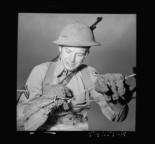 Untitled photo, possibly related to: Fort Belvoir, Virginia. A soldier handling barbed wire with special gloves which are clasped instead of sewn together