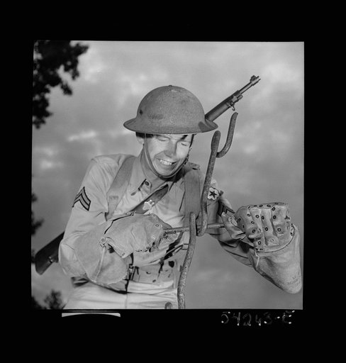 Untitled photo, possibly related to: Fort Belvoir, Virginia. A soldier handling barbed wire with special gloves which are clasped instead of sewn together