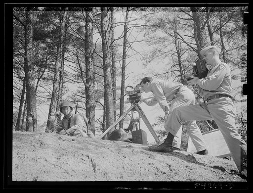 Fort Belvoir, Virginia. A soldier behind a bank throwing a hand grenade. Two photographers, watching the demonstration, appear in the picture