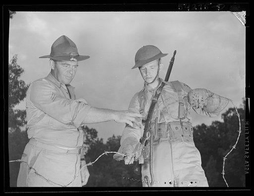 Fort Belvoir, Virginia. A soldier wearing special gloves getting instruction in handling barbed wire