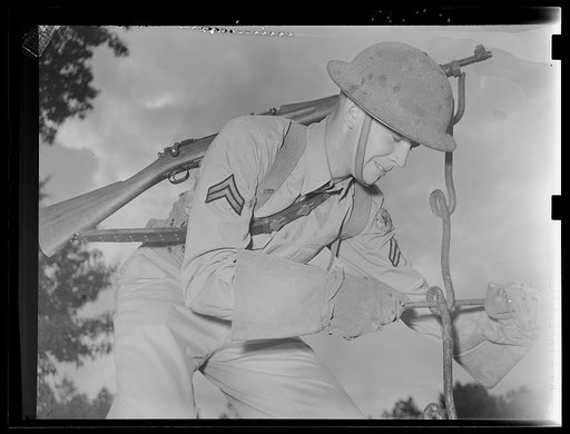 Fort Belvoir, Virginia. A soldier using a barbed wire anchor spike to screw in a picket. He is wearing special gloves that are made for handling barbed wire