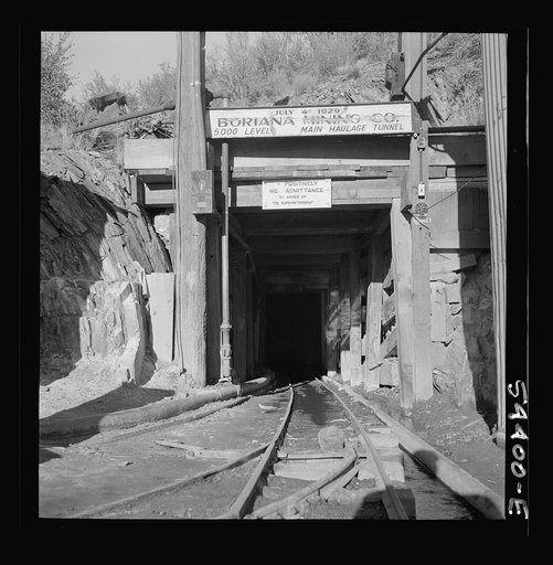 Untitled photo, possibly related to: Kingman (vicinity), Arizona. A miner going toward a train of mine cars at the entrance of the Boriana mining company. These cars carry tungsten ore to a concentrating plant in the same area. The mine is about forty miles from Kingman