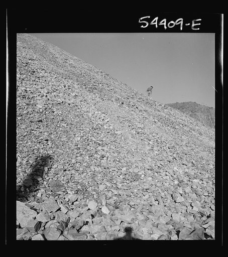 Untitled photo, possibly related to: Kingman (vicinity), Arizona. A huge waste pile, showing a workman near the center picking up still valuable pieces of tungsten ore, which is mined at the Boriana workings and processed at a nearby recovery plant