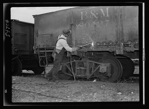 Boston and Maine railroad shops at Billerica, Massachusetts. Welder using special  flame to melt only head of rivet so it can be removed without burning other metal of car