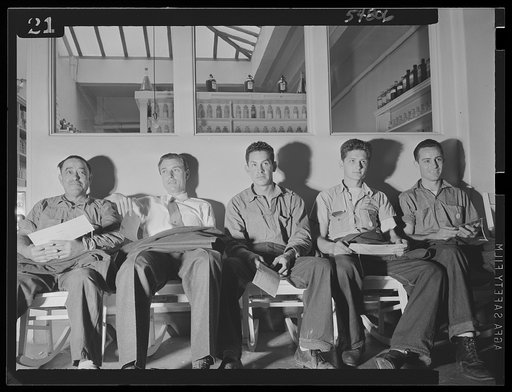 Willing blood donors await their turn to aid America's fighting men as the Red Cross blood donor mobile unit makes a visit to San Quentin. The men are waiting before the prison pharmacy in the San Quentin hospital
