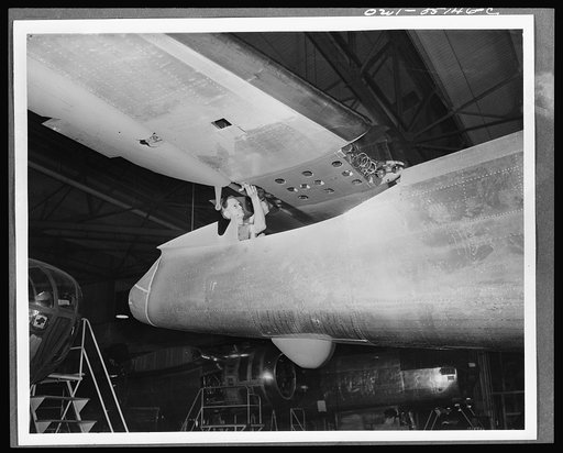The tail assembly for a North American B-25 bomber is lowered into place from an overhead crane on the final assembly floor