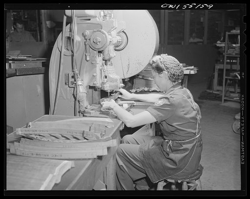 A woman punch-press operator turns out thousands of parts a day for North American B-25 bombers and P-51 fighters