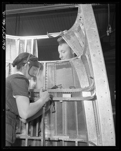 Two North American employees rivet the nacelle for a B-25 bomber. Woman and man. Women will probably be doing eighty percent of work at this plant next year. Now approximately twenty percent