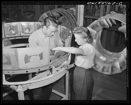 Men and women working together on the production front. Two North American employees assemble the engine cowling for a B-25 bomber
