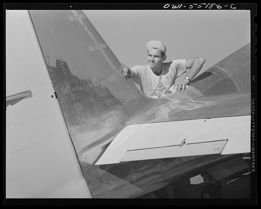 On North American's outdoor assembly line, a painter cleans the metal of a P-51 fighter prior to spraying on the olive drab camouflage of the United States Army Air Forces