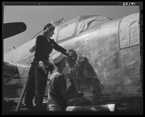 Two North American employees prepare a B-25 for painting. Man and woman. Note paper covered windows