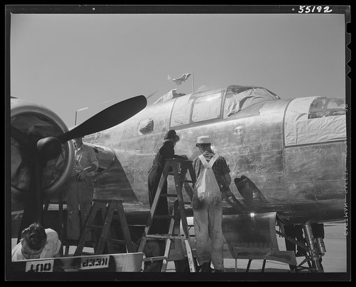 On North American's outdoor assembly line, two employees prepare a B-25 for paint, wiping off paint and chalk marks, etc.