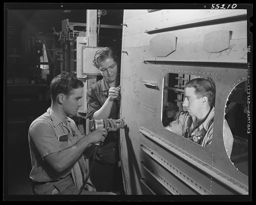 Kansas City, Kansas. A young woman and two men, employees of North American Aviation, Inc., riveting the skin assembly of a plane
