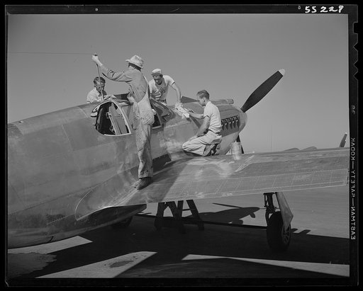 A North American P-51 fighter is cleaned by painters before receiving the olive drab paint of the United States Army Air Forces