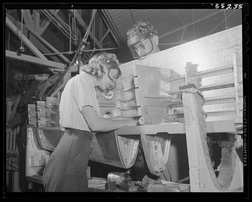 Inside the fuselage of a North American P-51 fighter, this woman employee assembles an electrical switch box