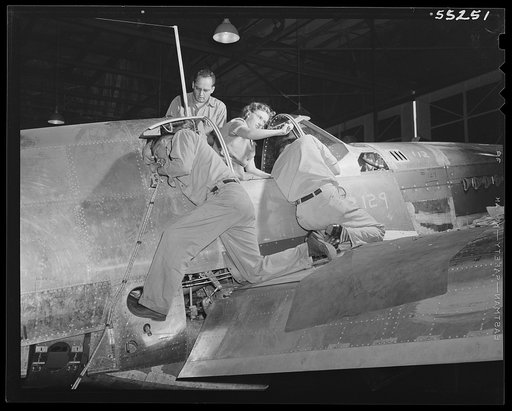 North American employees make additional installations on a P-51 fighter as it moves down the long final assembly line