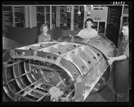 The skin is applied to the frame of a tank for a B-25 bomber. Women can be found in every department at North American Aviation, working together and with men. Next year approximately eighty percent of employees will be women; twenty percent at present