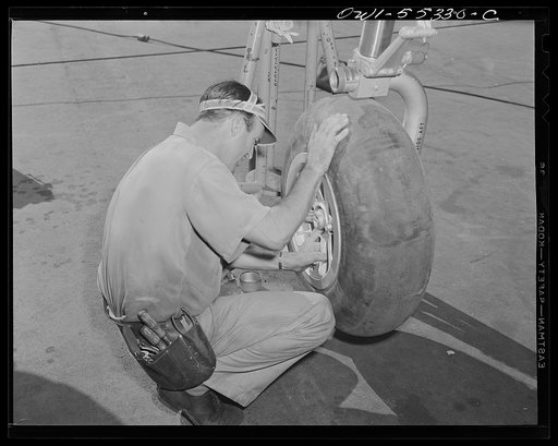 A wheel is mounted on the landing gear of a B-25 bomber on the final assembly line