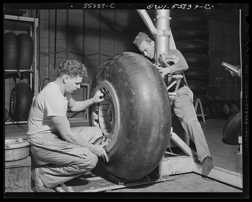 A huge rubber tire is mounted on the landing gear strut of a North American B-25 before it moves to the final assembly line
