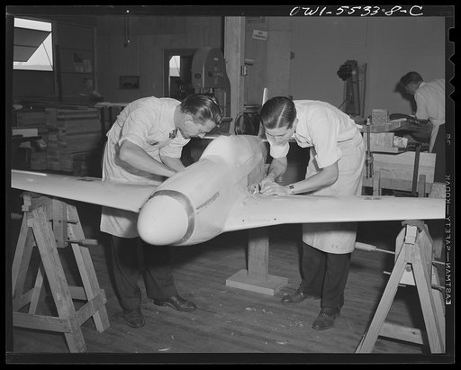 A scale wind tunnel model of North American Aviation's P-51 fighter is prepared by two model shop employees before another test is made to determine its flight characteristics. All measurements on these models are within two thousandths of an inch