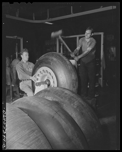 Huge rubber tires for North American B-25 bombers are mounted ready for assembly. The mallet is used in the balancing operation