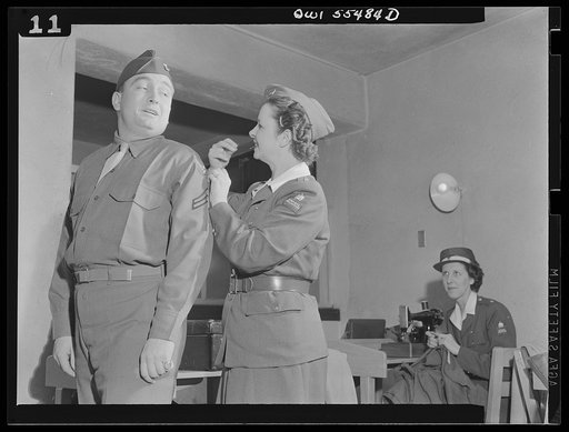 Catching that stitch in time, Mrs. Viola Schlaegel of the American Women's Volunteer Service unit at Glendale, California does a good turn for Corporal Hugh B. Helm of Lexington, Kentucky. Members of the American Women's Volunteer Service "Button Brigade" meet at least twice weekly at the Army Air F