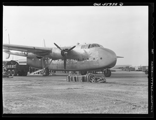 Front side view of C-82 shown at demonstration of equipment held by United States Army Air Forces. The after end of the fuselage opens to the complete height and width of the interior, which is square. To allow freight to be stowed directly from a truck, bottom of fuselage is the height of a standar