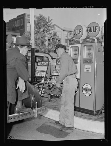 Gas station attendant at service station filling tank of a motorist's Dodge car. Washington, D.C.
