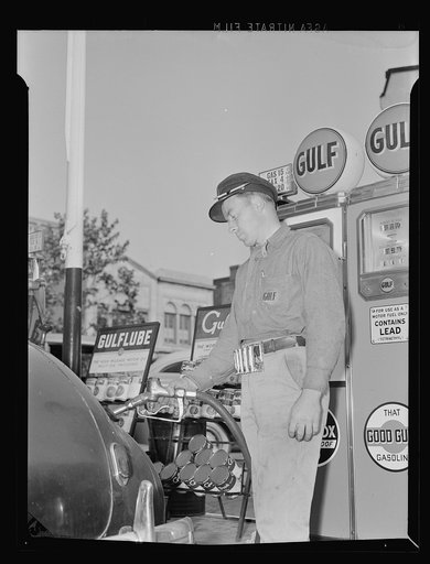 Gas station attendant at service station filling tank of a motorist's Dodge car. Washington, D.C.