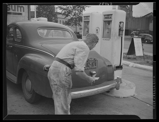 Gas station attendant checking ration coupons against license plate of Washington, D.C. Dodge automobile. Sign on sidewalk reads "Today's quota sold"