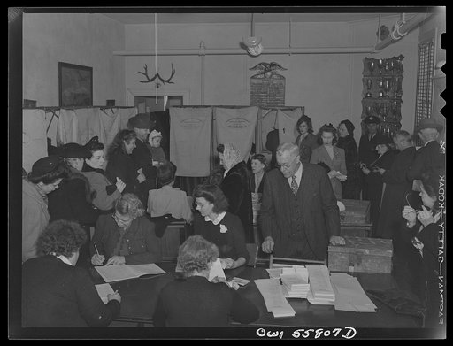 Arlington, Virginia. Interior of the firehouse with firemen's trophies in the background. Citizens' names are checked to see that each has paid his poll tax and registered. Ballots for the national presidental election are presented to each for secret voting in the "Douglas Collapsible" booths, and 