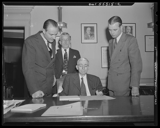 Washington, D.C. Mario Verdi (left), OWI (Office of War Information) radio commentator for Italy, visiting Assistant Postmaster General Perdum. Left to right: Mario Verdi, S.M. Weben, Assistant Postmaster General Perdum and E.J. Mahoney of the OWI