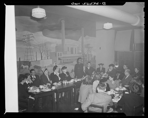 Untitled negative showing Maida Stewart Springer (International Ladies' Garment Workers Union), standing and speaking and Julia O'Connor Parker (International Brotherhood of Electrical Workers) (seated fourth from left) in room with mural. Anne Murkovich (American Federation of Hosiery Workers) and 