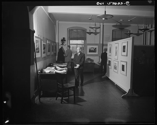 Installation of the United States Office of War Information (OWI) exhibit of original drawings and paintings by artists now in the armed forces. Preview, before shipping to Australia, held at the office of the Overseas Picture Division in the Auditor's Building