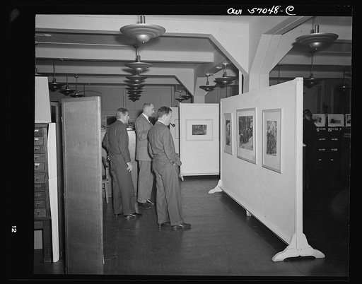 Installation of the United States Office of War Information (OWI) exhibit of original drawings and paintings by artists now in the armed forces. Preview, before shipping to Australia, held at the office of the Overseas Picture Division in the Auditor's Building
