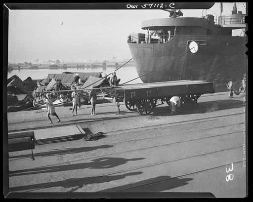 United States "lend-lease" program in eastern India. Indian coolies unload lend-lease steel tubing from a Liberty ship