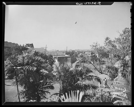 United States "lend-lease" program in eastern India. Tropical palms of India partially hide a great stockpile of war equipment at an Indian port city. Much of this material has been supplied to India under lend-lease. One of the protecting barrage balloons can be seen in the picture