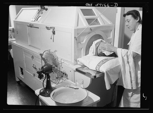 Melbourne, Australia. United States Army hospital. Patient receiving treatment in new fever machine which keeps temperature at 107 degrees (108 degrees is fatal). Note ice in basin and fan to cool head