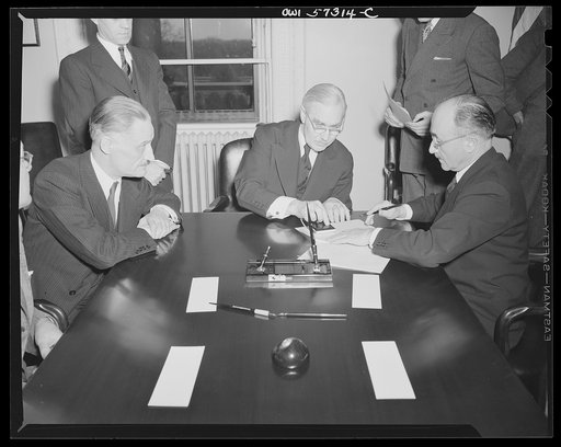 French conclude agreement on lend-lease and reverse lend-lease. Jean Monnet, representative of the French Provisional Government signs agreements. Left to right: Henri Bonnet, French Ambassador, Joseph C. Grew, Undersecretary of State and Jean Monnet