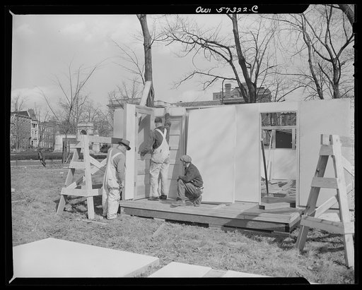 Houses for Britain. Workmen putting front door into place in model of pre-fabricated temporary emergency house of the type which it is planned to ship to Great Britain under lend-lease, at Scott Circle, Washington, D.C.