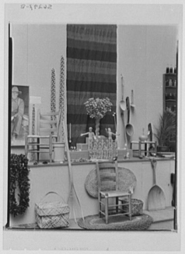 Rural arts exhibition held under the auspices of the Farm Security Administration (FSA) in the patio of the U.S. Department of Agriculture building. Left: photograph of chairmaker by Doris Ulmann; chair, Kentucky; basket, Puerto Rico, Virgin Islands; wooden chains made from one single piece of wood 