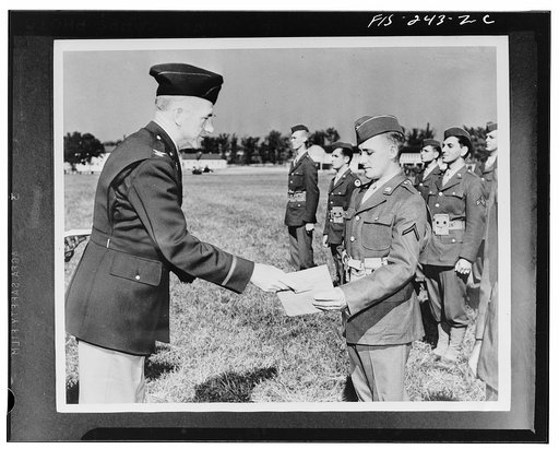 Camp Crowder, Missouri. Private William J. De Groot, receiving from his regimental commander, Colonel Sylvester Nortner, three hundred sixty-four dollars and ten cents in war bonds and stamps, awarded him by a Detroit auto parts manufacturer for an idea which resulted in a production speedup